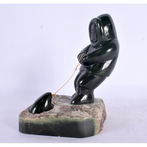 369 - A LOVELY NORTH AMERICAN INUIT CARVED JADE FIGURE OF A SEAL HUNTER modelled upon a naturalistic base.... 