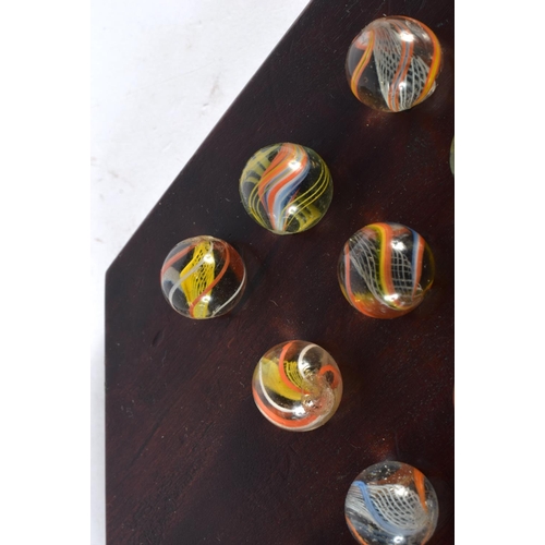 381 - A SET OF ANTIQUE SOLITAIRE GLASS MARBLES. Board 22 cm wide. Marble 1 cm approx wide. (qty)