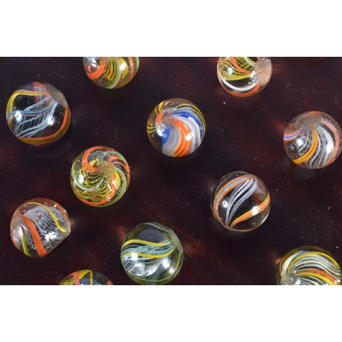 381 - A SET OF ANTIQUE SOLITAIRE GLASS MARBLES. Board 22 cm wide. Marble 1 cm approx wide. (qty)