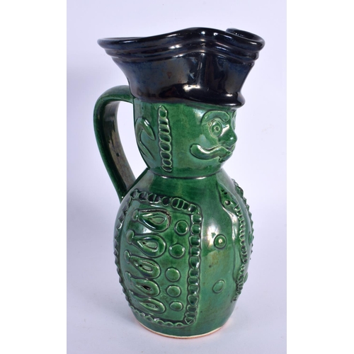 130 - AN UNUSUAL ANTIQUE GREEN GLAZED POTTERY CHARACTER JUG. 21 cm high.