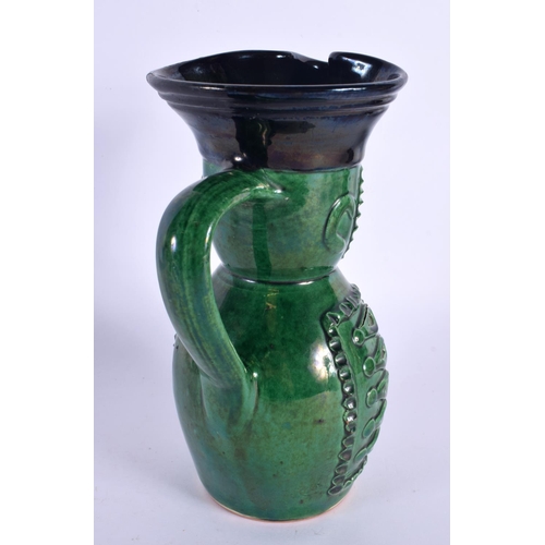 130 - AN UNUSUAL ANTIQUE GREEN GLAZED POTTERY CHARACTER JUG. 21 cm high.