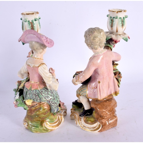 236 - DERBY PORCELAIN SEATED PAIR OF CANDLESTICK FIGURES, MODELLED AS A MAN WITH A HAT FILLED WITH FRUIT A... 