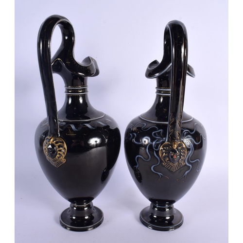 79 - A LARGE PAIR OF MID 19TH CENTURY ENGLISH BLACK POTTERY EWERS painted with portraits. 32 cm high.