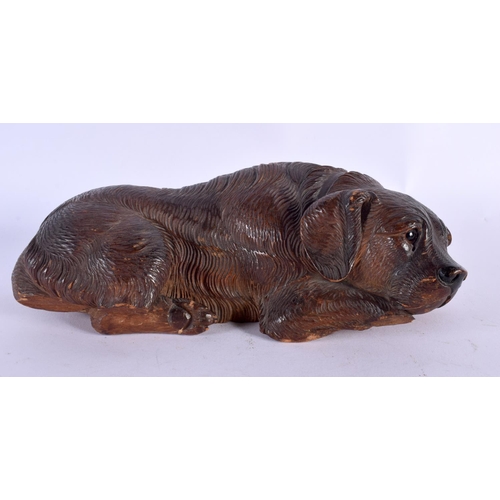 307 - A 19TH CENTURY BAVARIAN BLACK FOREST FIGURE OF A SLEEPING HOUND modelled recumbent 22 cm x 10 cm.