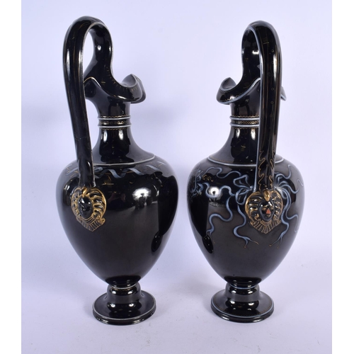 350 - A LARGE PAIR OF MID 19TH CENTURY ENGLISH BLACK POTTERY EWERS painted with portraits. 32 cm high.