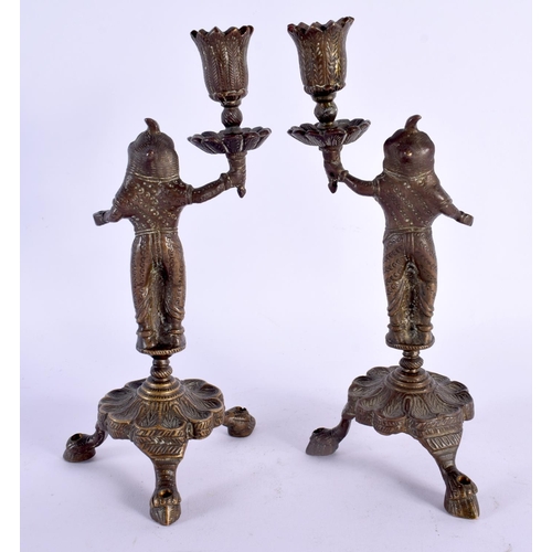 355 - A PAIR OF 19TH CENTURY MIDDLE EASTERN INDIAN BRONZE CANDLESTICKS formed as deities holding aloft sco... 