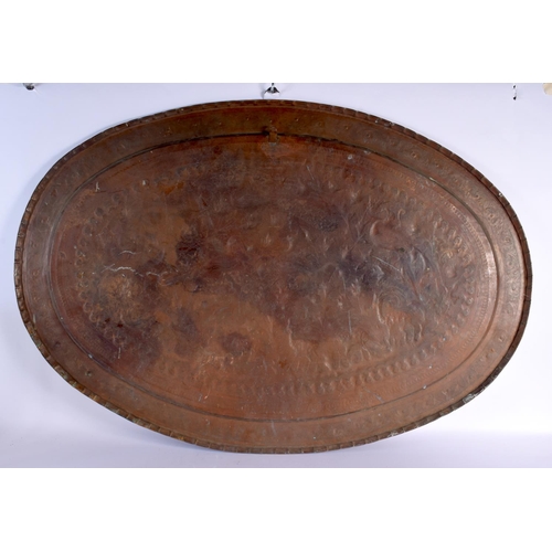 568 - A VERY LARGE ANTIQUE PERSIAN TINNED COPPER OVAL TRAY decorated with repousse birds. 98 cm x 67 cm.