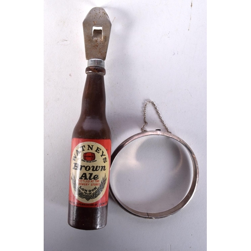 1014 - A SILVER BANGLE together with a Watneys brown ale bottle opener. Largest 14 cm long. (2)