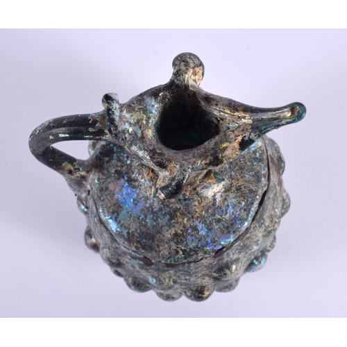 7 - AN EARLY IRIDESCENT DIMPLED GLASS JUG probably Roman. 18 cm x 10 cm.