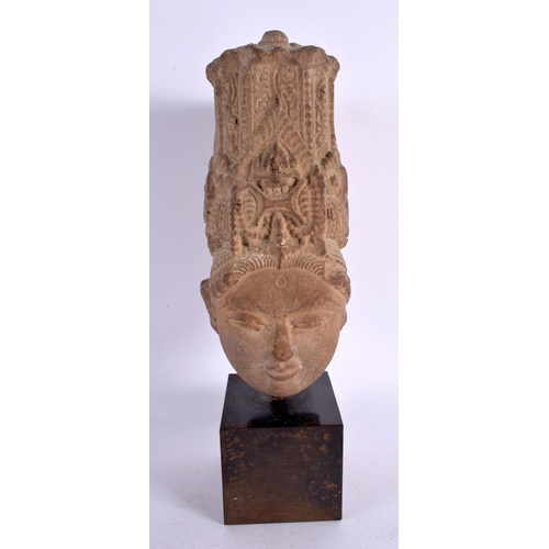 125 - A 16TH/17TH CENTURY INDIAN CARVED STONE HEAD OF A BUDDHA modelled upon a bronze base. 28 cm high.