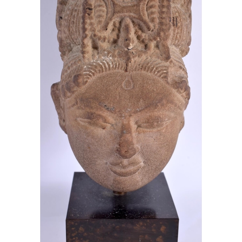 125 - A 16TH/17TH CENTURY INDIAN CARVED STONE HEAD OF A BUDDHA modelled upon a bronze base. 28 cm high.