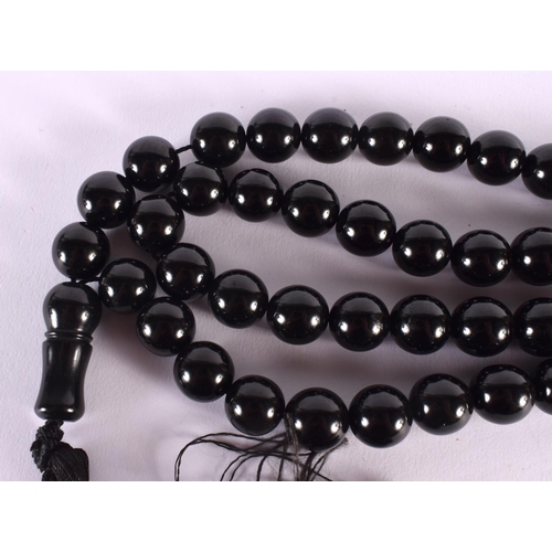 311 - A TURKISH MIDDLE EASTERN BLACK AMBER TYPE NECKLACE. 270 grams. 146 cm long, each bead 1.75 cm wide.