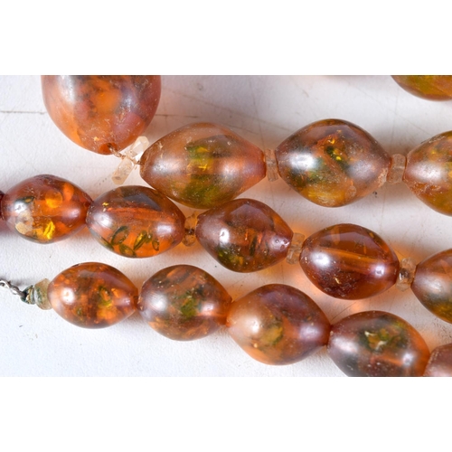 1018 - AN AMBER TYPE NECKLACE. 53 grams. 70 cm long, largest bead 3 cm x 2 cm.