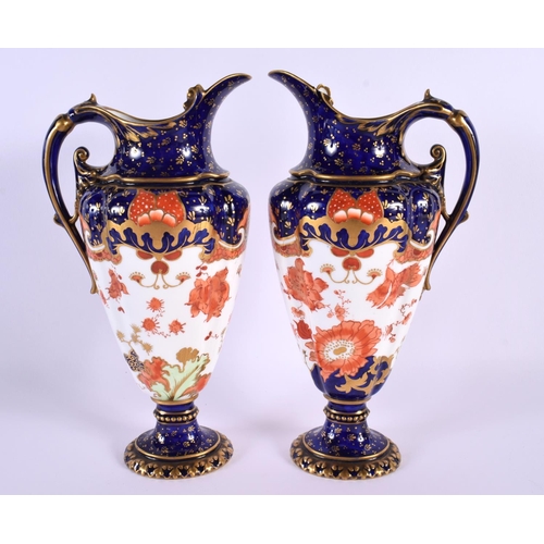 119 - A PAIR OF ROYAL CROWN DERBY PORCELAIN EWERS painted with flowers. 22 cm high.