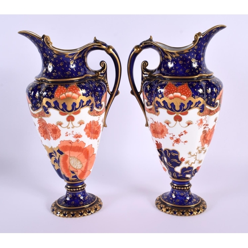 119 - A PAIR OF ROYAL CROWN DERBY PORCELAIN EWERS painted with flowers. 22 cm high.