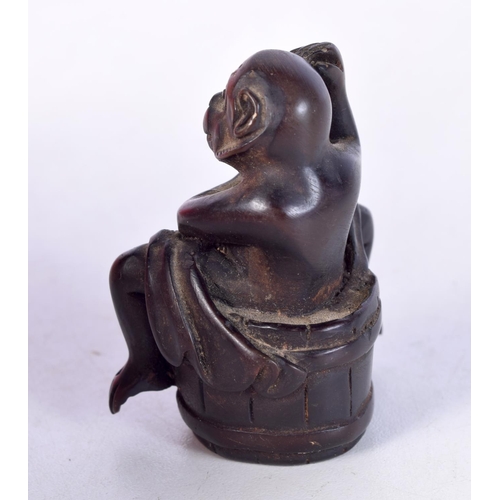 1404 - A CARVED WOOD NETSUKE IN THE FORM OF A MONKEY SITTING ON A BARREL. 5cm x 4cm