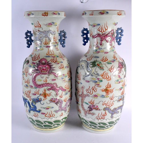 2121 - A LARGE PAIR OF CHINESE TWIN HANDLED FAMILLE ROSE VASES 20th Century, overlaid in relief with dragon... 