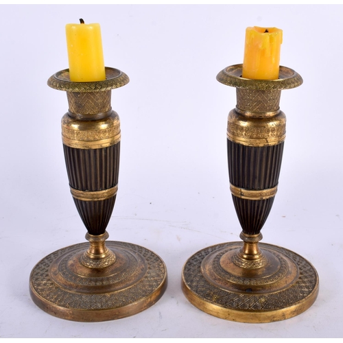 14 - A PAIR OF EARLY 19TH CENTURY FRENCH EMPIRE TWO TONE BRONZE CANDLESTICKS formed as tapered ribbed col... 