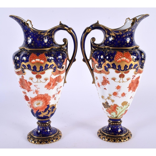 137 - A PAIR OF ROYAL CROWN DERBY PORCELAIN EWERS painted with foliage. 23 cm high.