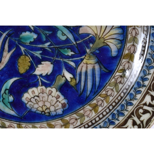 144 - AN 18TH/19TH CENTURY MIDDLE EASTERN IZNIK POTTERY DISH painted with flowers. 27 cm diameter.