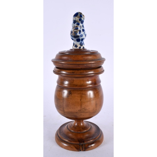 594 - AN ANTIQUE TREEN CARVED WOOD JAR AND COVER with delft finial. 23 cm high.