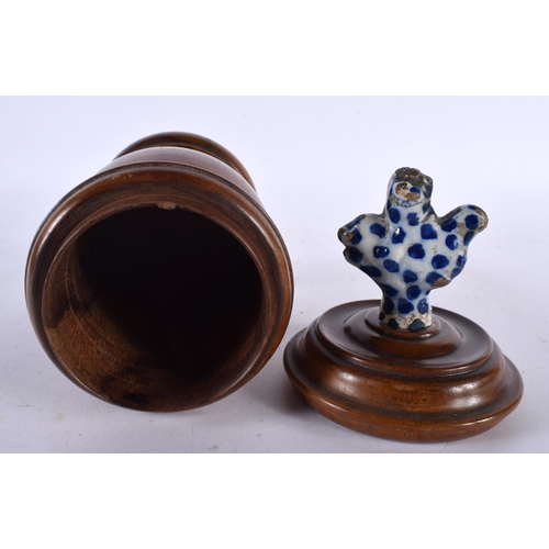 594 - AN ANTIQUE TREEN CARVED WOOD JAR AND COVER with delft finial. 23 cm high.