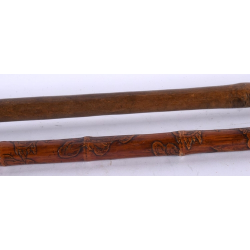 757 - AN EARLY 20TH CENTURY TRIBAL CARVED WOOD STAFF together with a Japanese bamboo walking cane. Largest... 