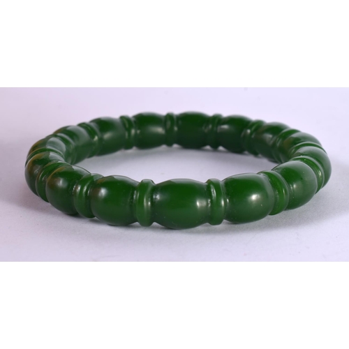 1300 - A RIBBED GREEN JADE BANGLE.  Internal 5.7cm, weight 43.7g