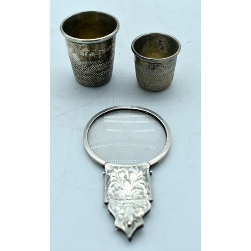 1764 - A SILVER MAGNIFYING MIRROR and a two white metal thimbles. 100 grams overall. Largest 11cm long. (3)