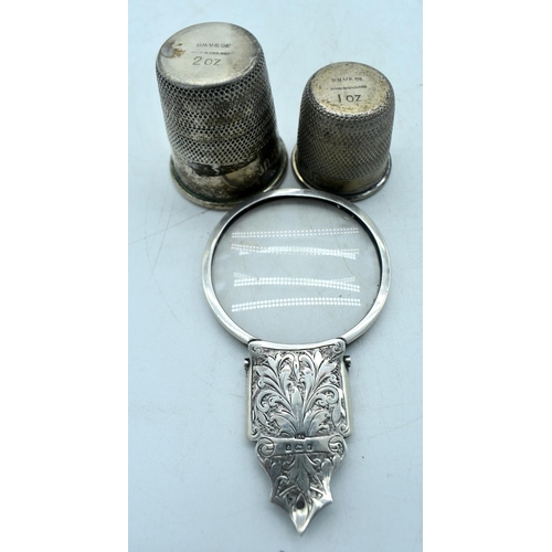 1764 - A SILVER MAGNIFYING MIRROR and a two white metal thimbles. 100 grams overall. Largest 11cm long. (3)