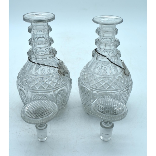 1784 - A PAIR OF REGENCY CUT GLASS DECANTERS with silver decanter labels. 25 cm high.