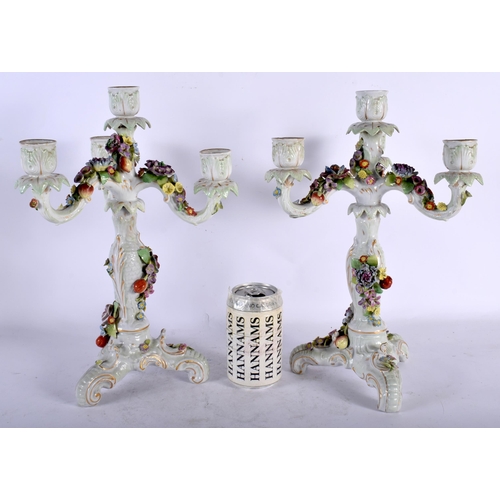 131 - A PAIR OF EARLY 20TH CENTURY CONTINENTAL PORCELAIN TRIPLE BRANCH CANDLESTICKS overlaid with foliage.... 