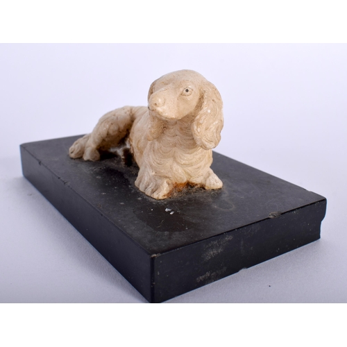 518B - A 19TH CENTURY EUROPEAN CARVED ALABASTER FIGURE OF A SEATED HOUND upon a marble base. 10 cm x 5 cm.