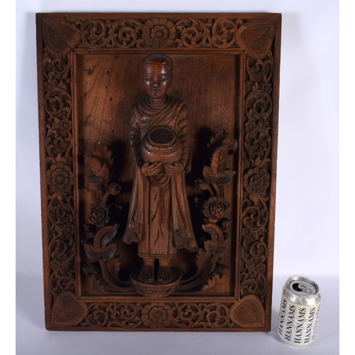 666 - A LARGE 19TH CENTURY INDIAN CARVED WOOD TEMPLE PANEL depicting a buddhistic figure standing upon fla... 