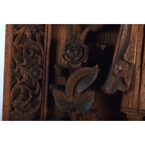 666 - A LARGE 19TH CENTURY INDIAN CARVED WOOD TEMPLE PANEL depicting a buddhistic figure standing upon fla... 