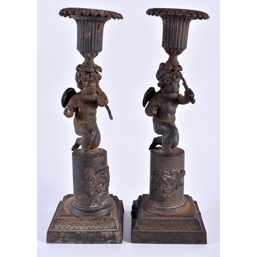 330 - A RARE PAIR OF EARLY 19TH CENTURY FRENCH CAST IRON CANDLESTICKS formed as putti holding bows, upon p... 