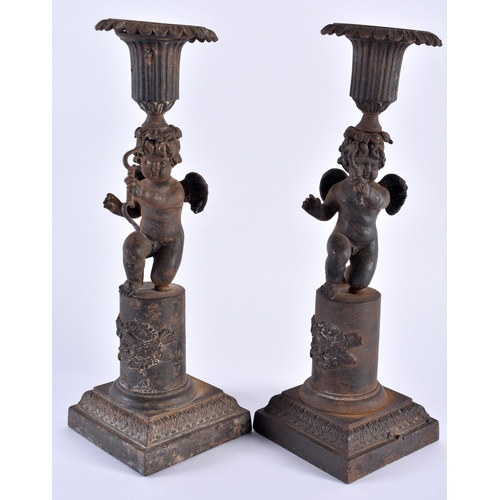 330 - A RARE PAIR OF EARLY 19TH CENTURY FRENCH CAST IRON CANDLESTICKS formed as putti holding bows, upon p... 