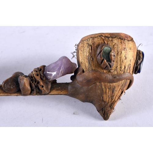 452 - AN UNUSUAL TRIBAL CARVED WOOD AND NUT GEM SET PIPE formed with a grotesque figure. 20 cm long.