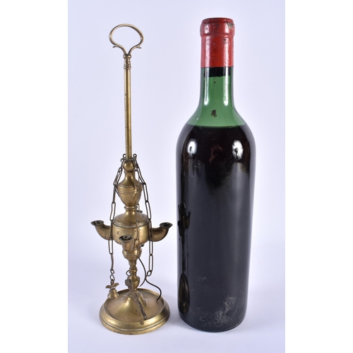 514 - AN EARLY MIDDLE EASTERN ISLAMIC OIL LAMP together with a bottle of 1967 Listrac wine. 32 cm high. (2... 