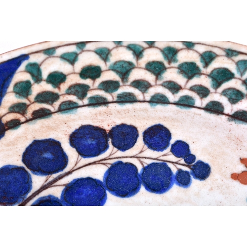 527 - A LARGE TURKISH KUTAHYA POTTERY DISH painted with a figure amongst foliage. 30 cm diameter.