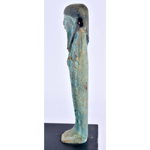 549 - AN EGYPTIAN FAIENCE GLAZED USHABTI FIGURE upon a later ebonised base. Ushabti 11 cm high.