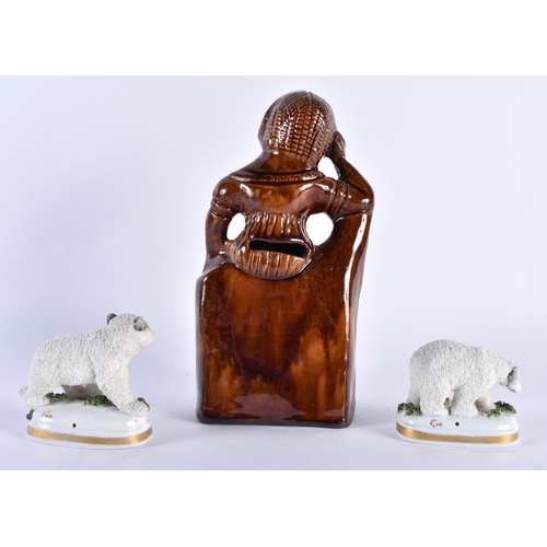 754 - AN ANTIQUE TREACLE GLAZED FIGURAL MONEY BOX together with a pair of Continental porcelain polar bear... 