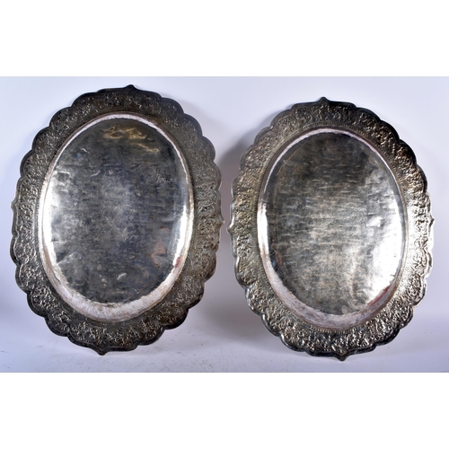 75C - A LARGE PAIR OF 19TH CENTURY INDIAN SILVER REPOUSSE SERVING TRAYS decorated with foliage and vines. ... 