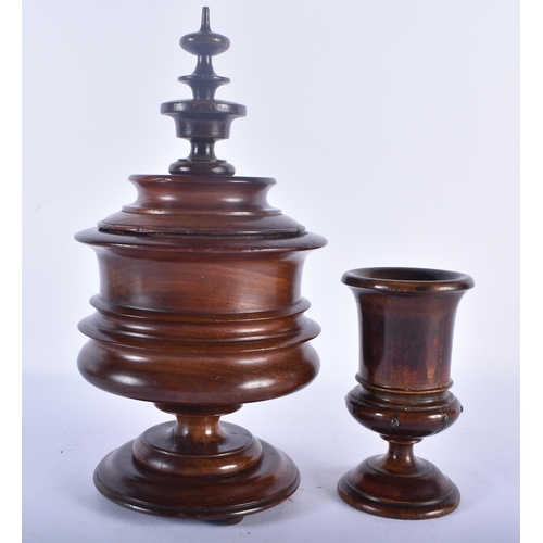 509 - A LARGE ANTIQUE TREEN CARVED WOOD VASE AND COVER together with a similar vase. Largest 27cm high.