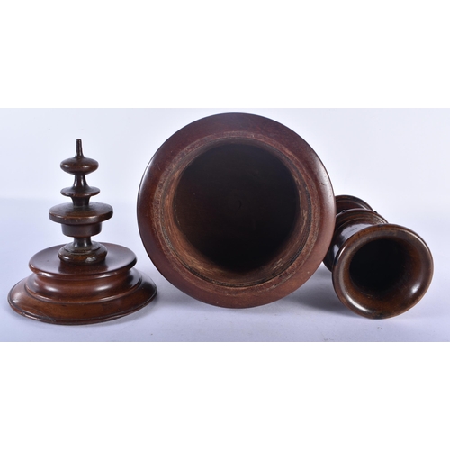 509 - A LARGE ANTIQUE TREEN CARVED WOOD VASE AND COVER together with a similar vase. Largest 27cm high.