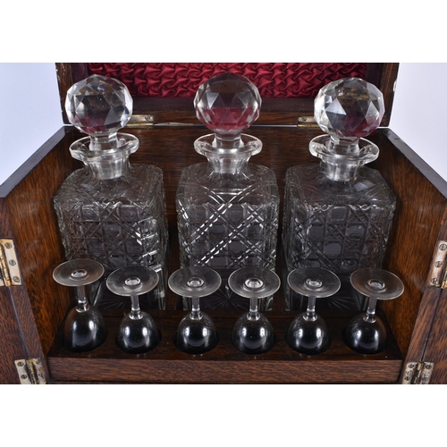 554 - A LARGE LATE VICTORIAN OAK CASED TANTALUS the top and front opening to reveal a fully fitted interio... 