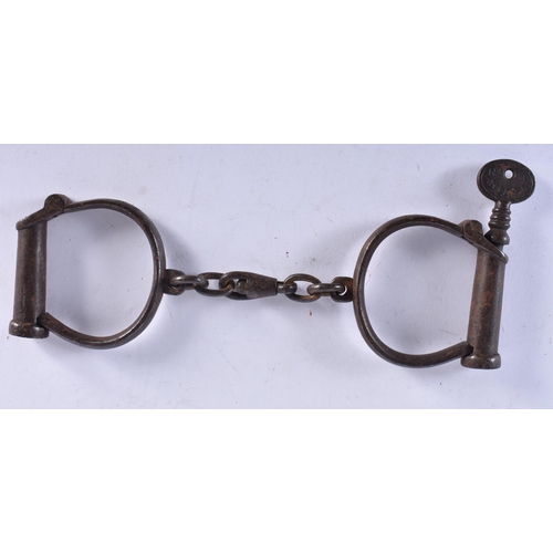 702 - A PAIR OF ANTIQUE HANDCUFFS together with a similar padlock. Largest 24 cm long. (3)