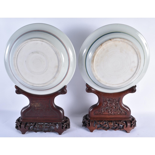 858 - A LARGE PAIR OF CHINESE PORCELAIN PLATES upon a fitted hardwood base. 52 cm x 25cm.