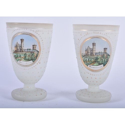 95 - A PAIR OF ANTIQUE OPALINE JEWELLED GLASS BEAKERS painted with German landmarks. 11cm x 6 cm.