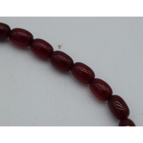 1003 - A CHERRY AMBER NECKLACE. 54 grams. 76 cm long, largest bead 2.5 cm x 1.75 cm.